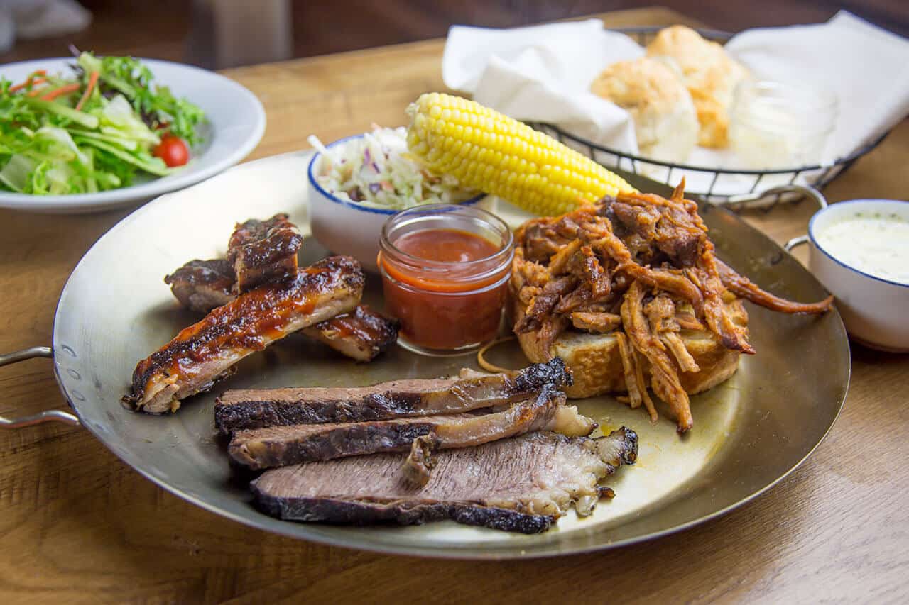 barbecue platter with salad, corn, coleslaw, and biscuts