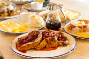 french toast covered in berries, eggs, syrup, and other breakfast foods